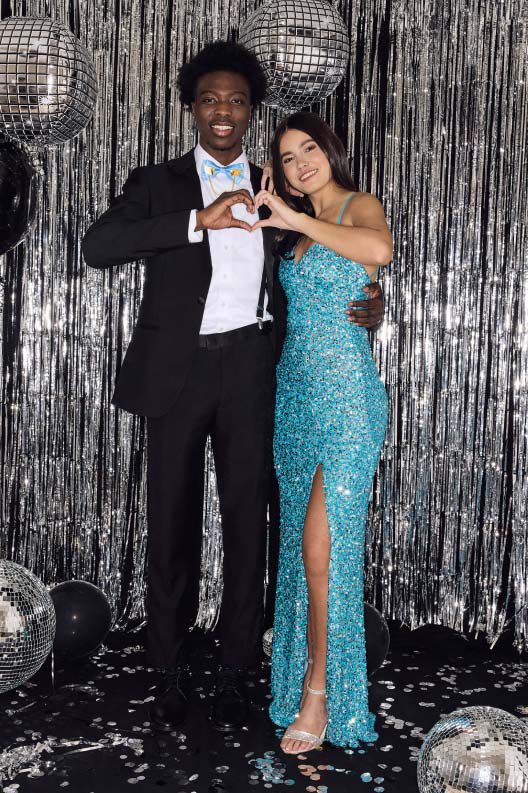 prom couple making hear hands in front of streamers