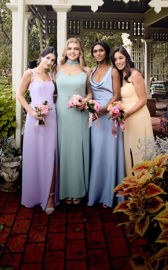 group of four bridesmaids in pastel colors holding bouquets