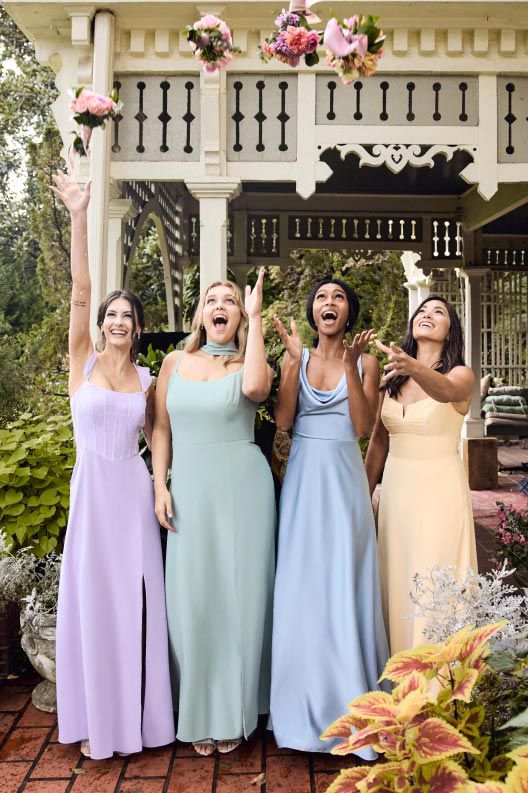four bridesmaids standing outside throwing their bouquets in the air