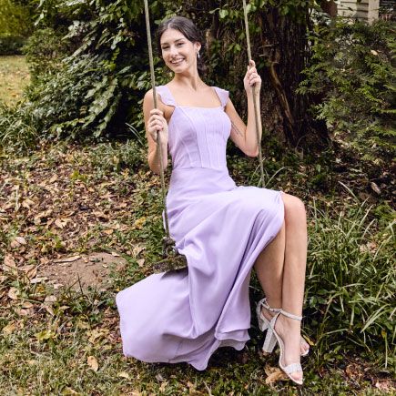 bridesmaid in purple dress swinging on a swing outside
