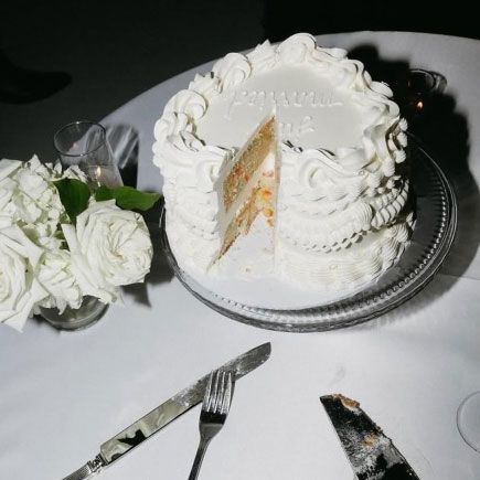 white wedding cake with a piece cut out sitting on a table