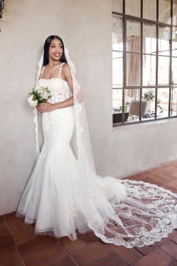 woman in wedding dress holding bouquet with long veil