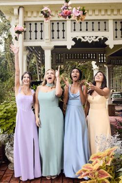four bridesmaids standing outside throwing their bouquets in the air