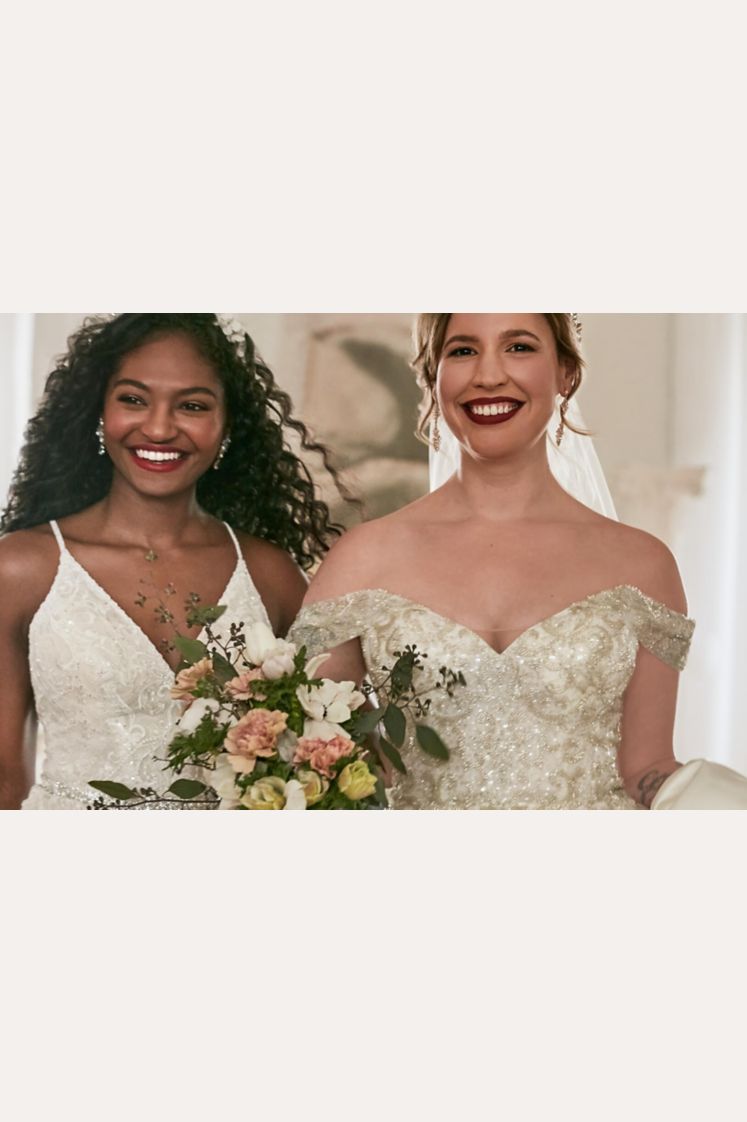 2 brides wearing wedding dresses walking and holding a bouquet