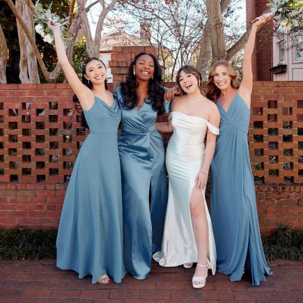 bride with her bridesmaids posing next to a brick wall