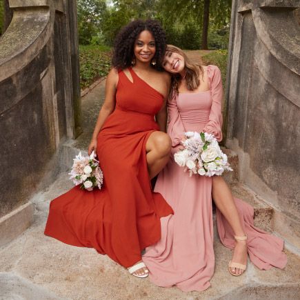 two bridesmaids sitting on steps with bouquets