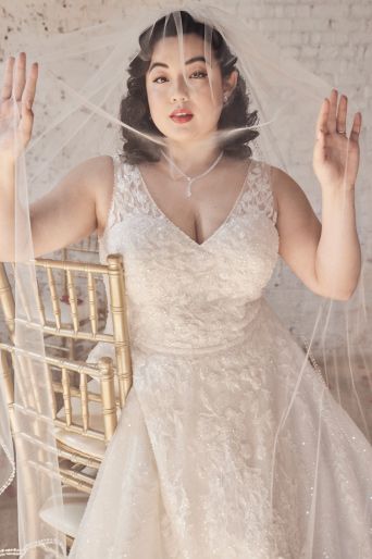 Bride with her hands up inside her cathedral veil