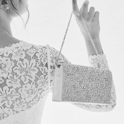 closeup of a bride dangling a handbag from her finger