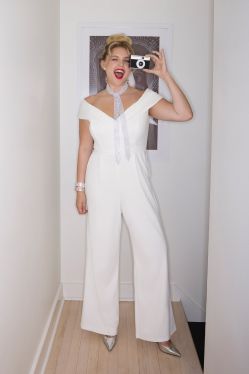 woman in bridal jumpsuit in a hallway holding a camera