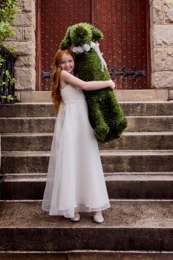 girl in flower girl dress holding a topiary dog