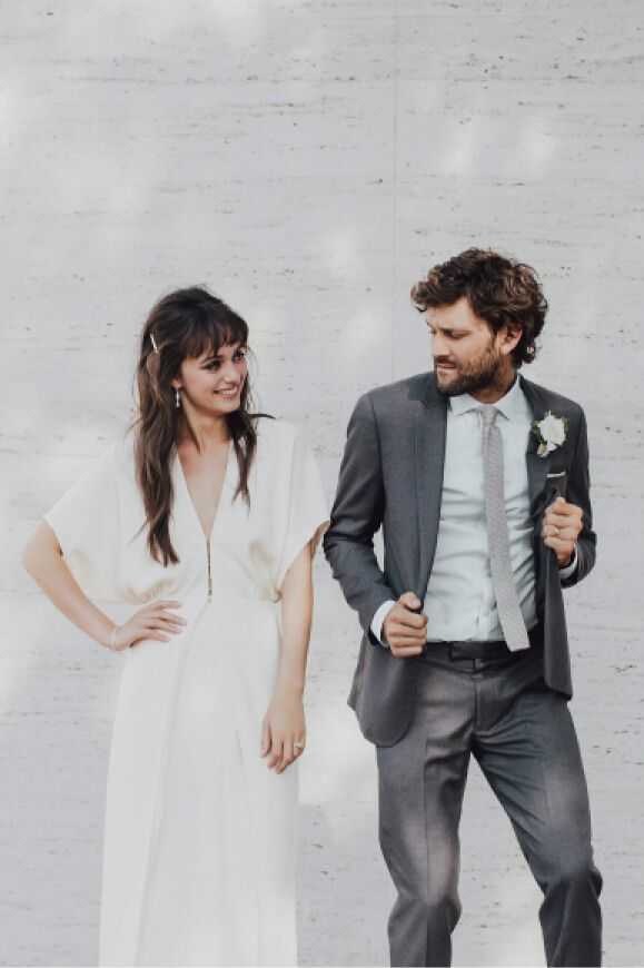 woman in a white dress standing next to a dancing man in a gray tuxeo