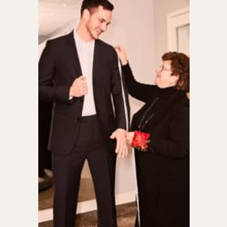 groom in black tuxedo getting jacket measured by a store associate