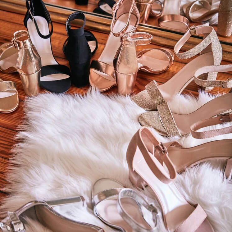 several pairs of shoes laid out on fur on a carpet