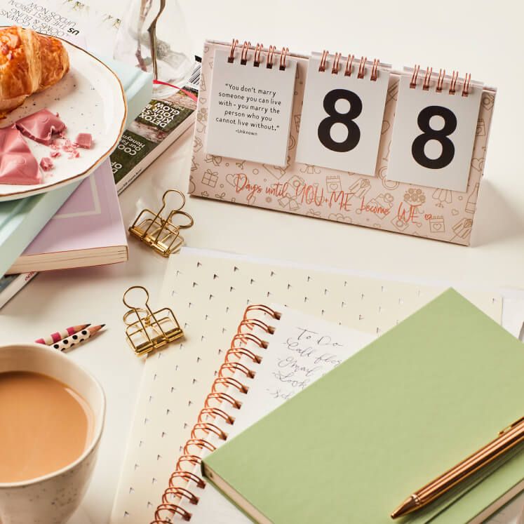 notebook, coffee cup, clips, and calendar on a table