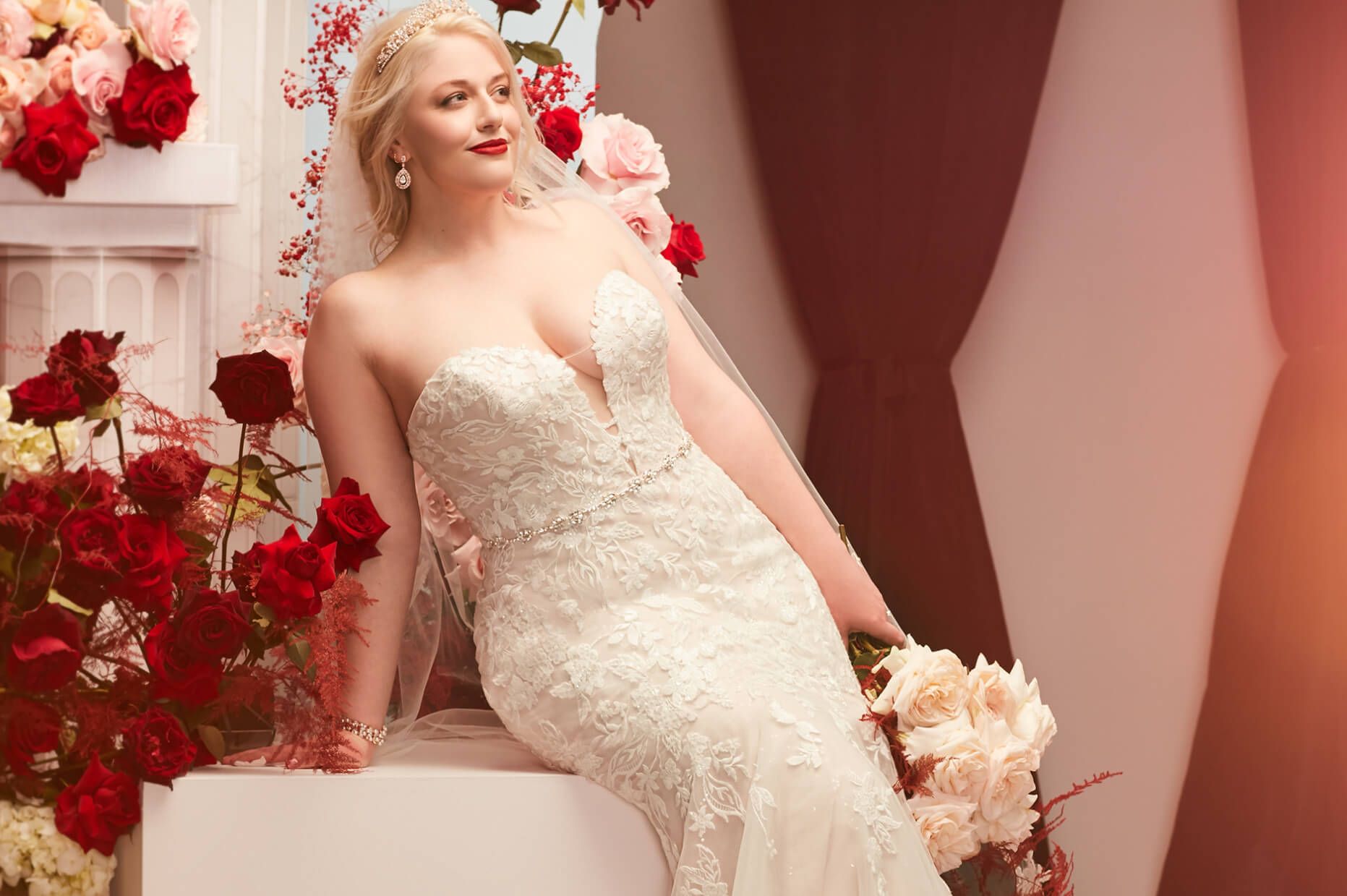 bride wearing wedding dress holding bouquet and sitting on a block