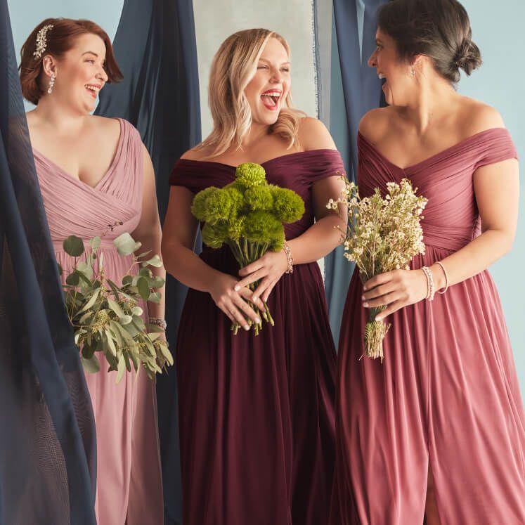 3 bridesmaids wearing different dresses standing together and laughing