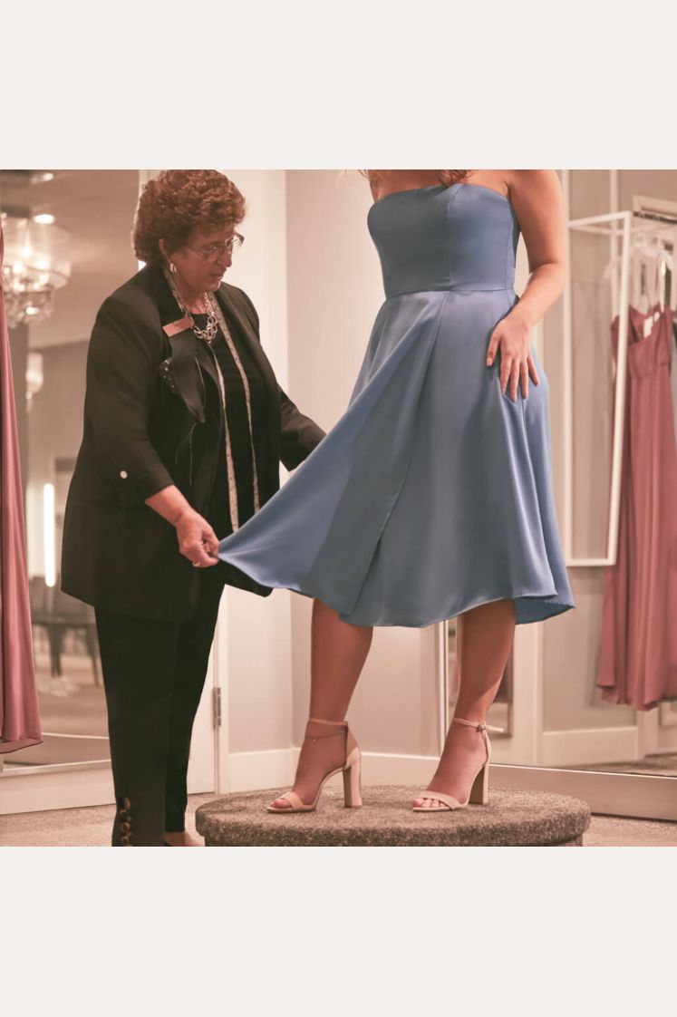 store associate assisting a bridesmaid with a dress fitting