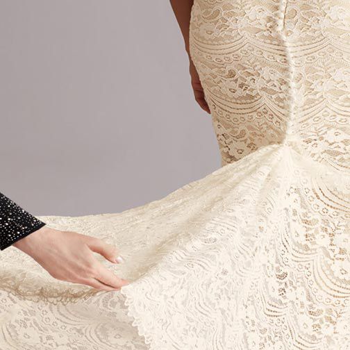 closeup of stylist fanning out wedding dress train