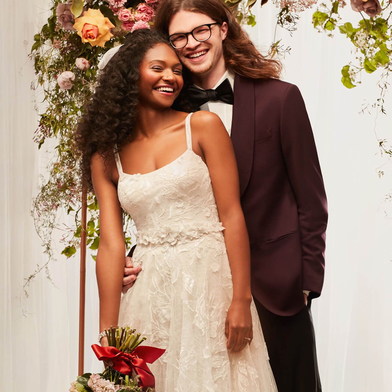 bride and groom embracing under a flower arrangement