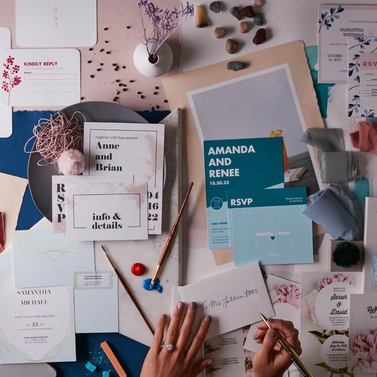 hands writing on an envelope with stationery laid out on a table