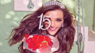 young woman wearing a veil and holding a cake with 15 on it
