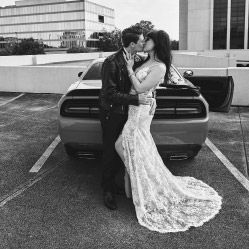 bride and groom kissing while leaning on the back of a car