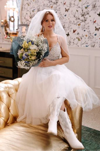 bride holding large bouquet sitting on the edge of a couch