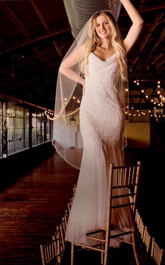 woman in wedding dress standing on a chair in a banquet hall