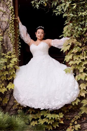 woman in wedding dress standing in window frame surrounded by foliage