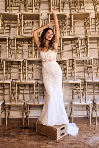 woman in wedding dress standing in front of stacks of chairs