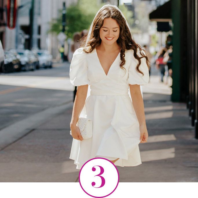 bride holding a handbag and walking down the sidewalk