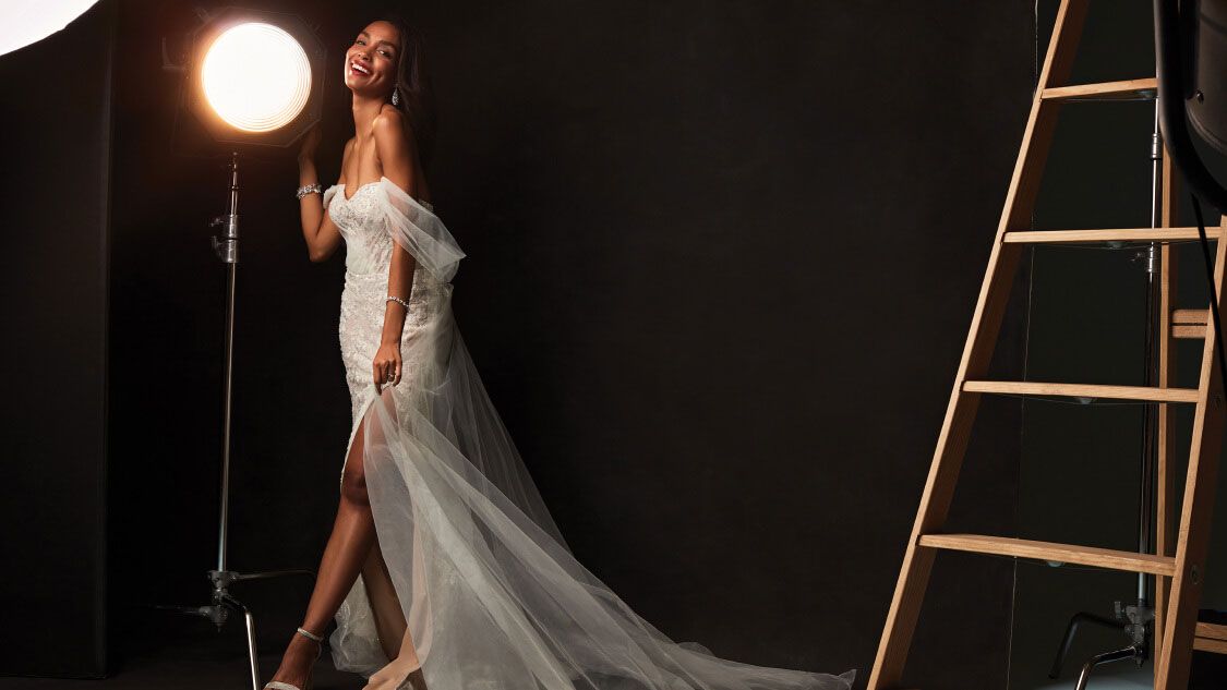 bride in wedding dress standing on set touching a spotlight