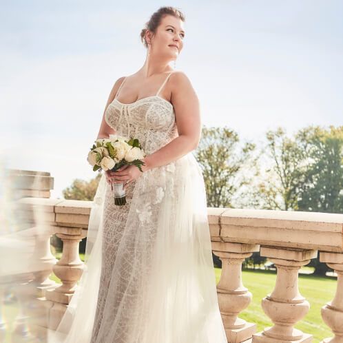 bride holding a bouquet and looking over a balcony