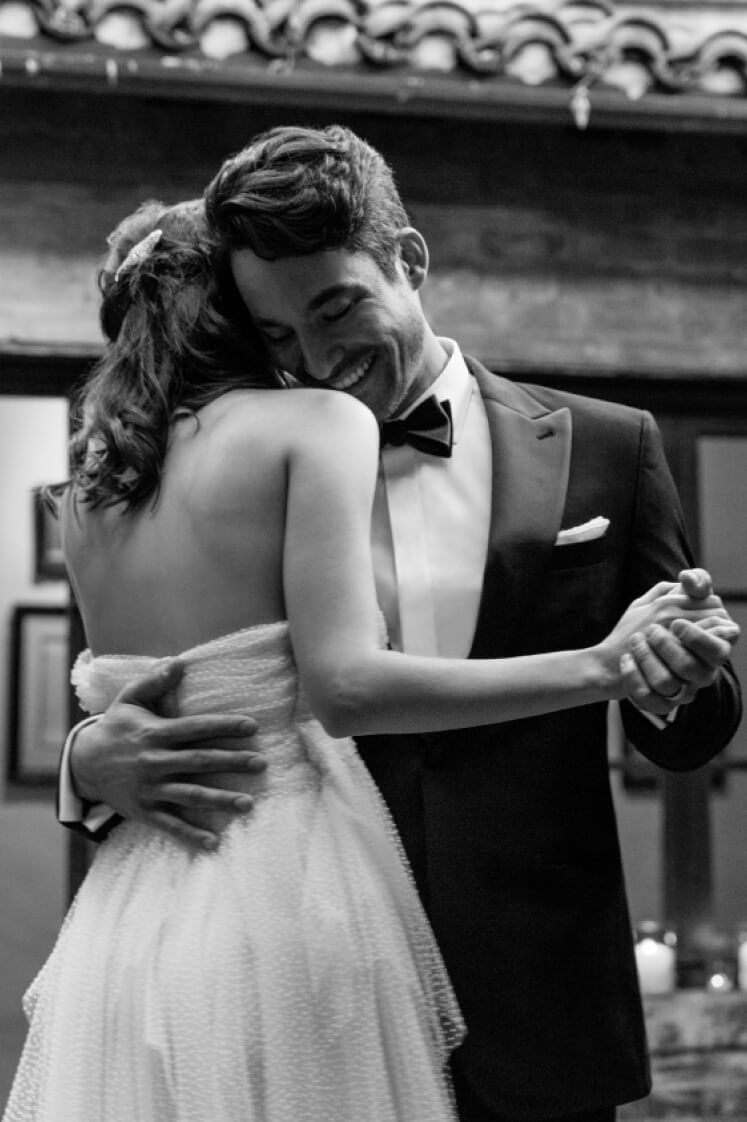 groom with arm around bride dancing