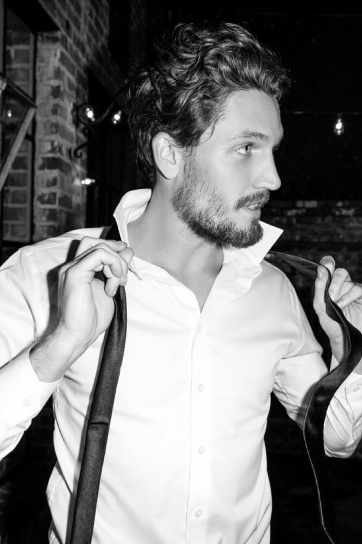 man wearing a button down shirt taking off necktie