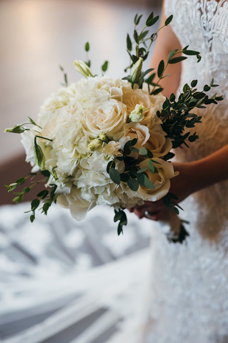side view of bride holding a bouquet of white roses