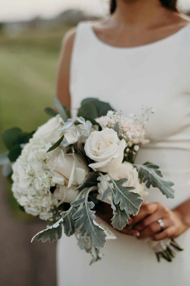 bride holding a bouquet of white roses in one hand
