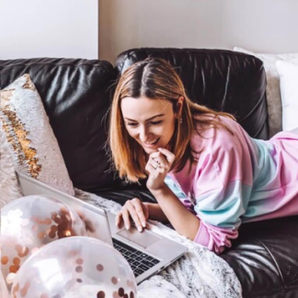 woman laying on a couch looking at a laptop