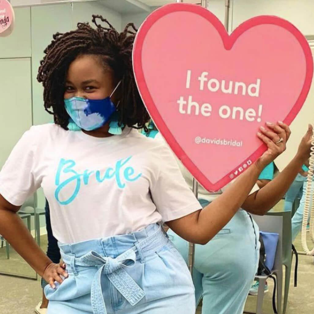 woman wearing a mask holding a heart shaped sign in a store