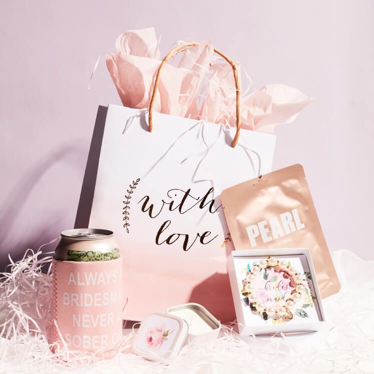 gift bag, sheet mask, bracelet, and drink sleeve displayed on a table