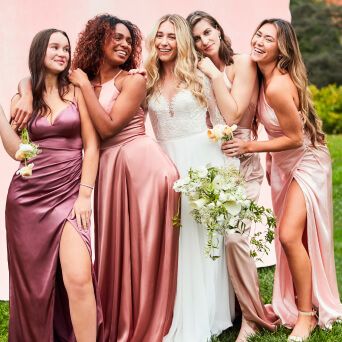 bride standing with bridesmaids outside in front of a pink backdrop