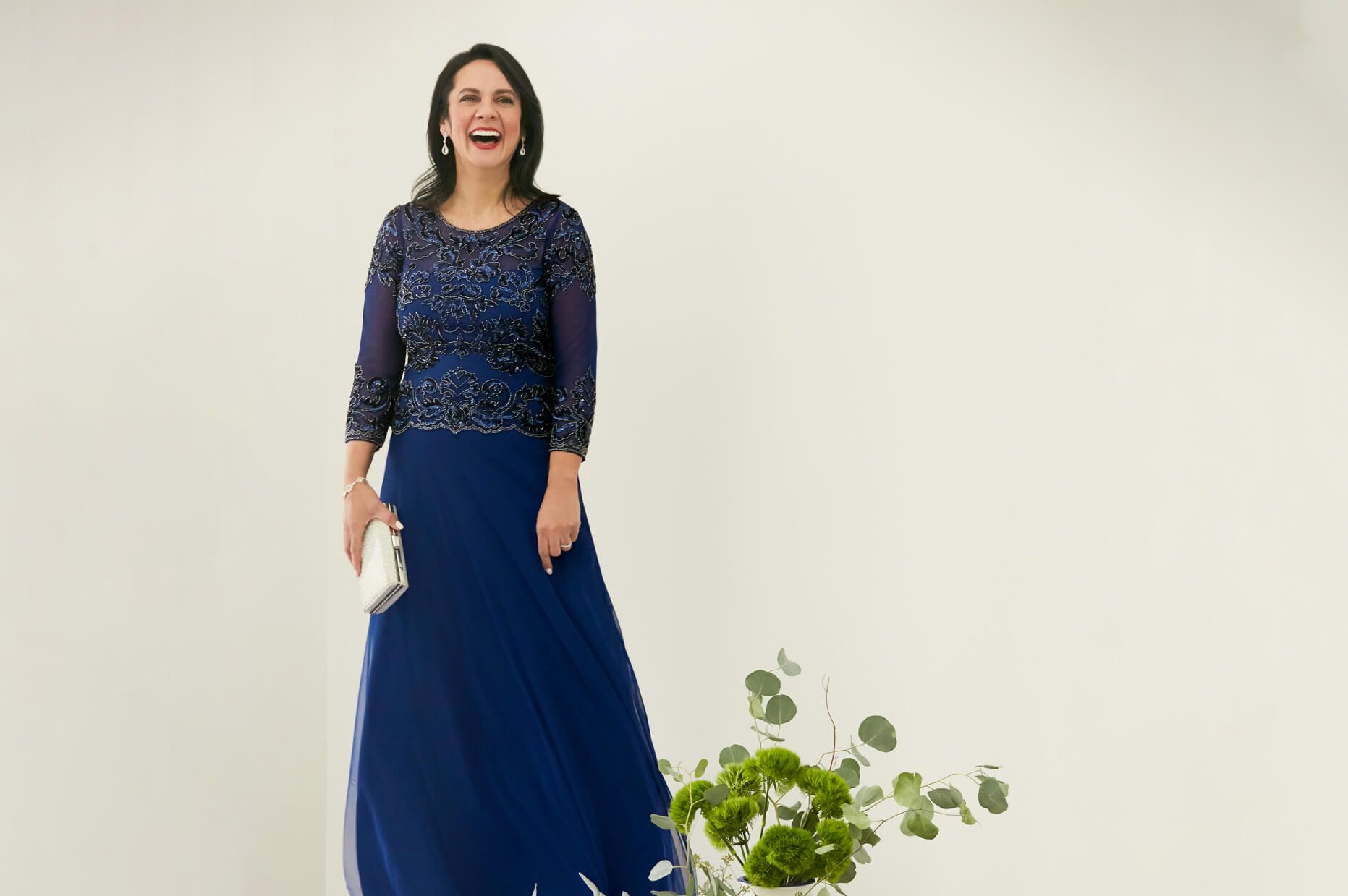woman in blue dress with sleeves holding a clutch and smiling