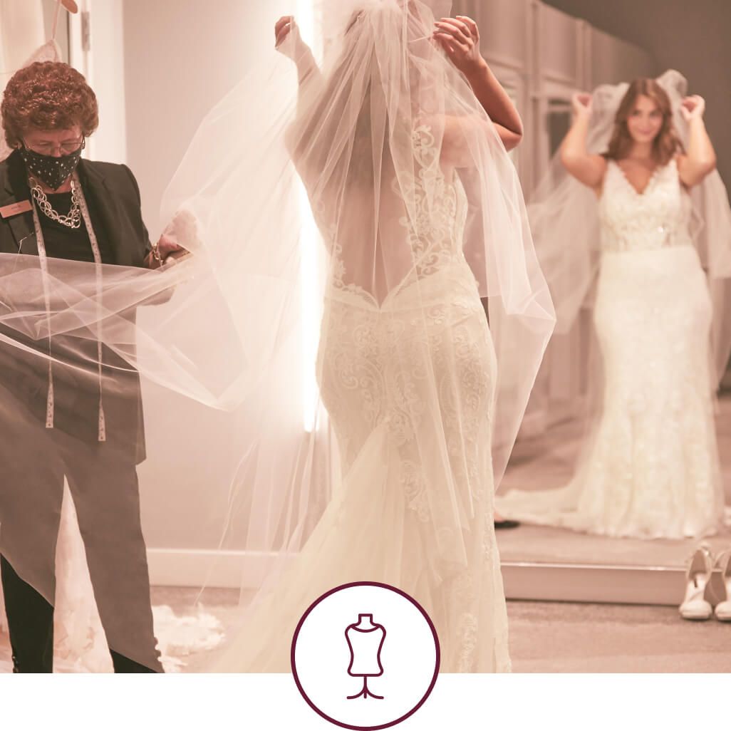 store associate helping bride with wedding dress fitting